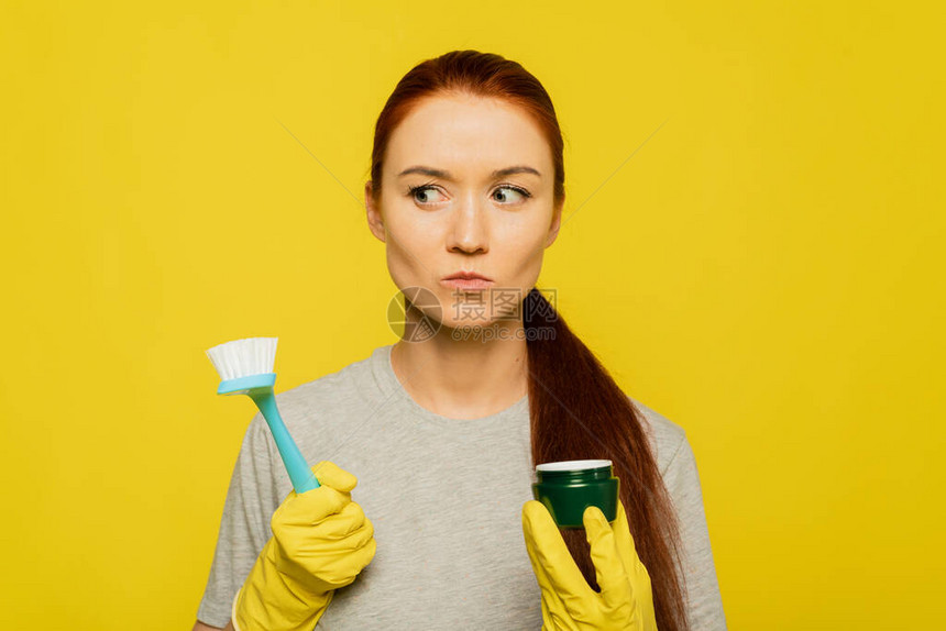 选择奶油和皮肤磨砂膏一个漂亮的女人拿着一把洗碗刷和一个戴着黄色橡胶手套的保湿面罩皮肤清洁旧皮肤图片