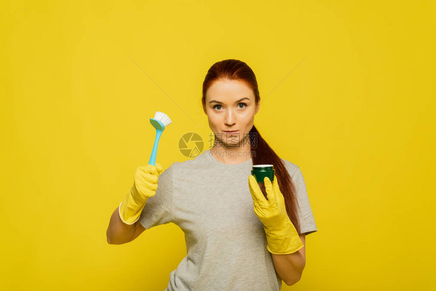 可爱的美女拿着洗碗刷子和黄色橡胶手套上的湿润面罩图片