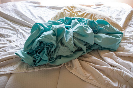 洗衣用过的象牙枕头白床上用过的绿松石圆状床单选择焦点图片