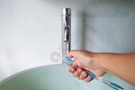 女人右手洗刷绿浴盆上的牙刷图片
