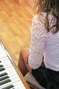 年轻钢琴家女孩的腿在钢琴旁边钢琴家女孩的钢琴键和腿键盘乐图片