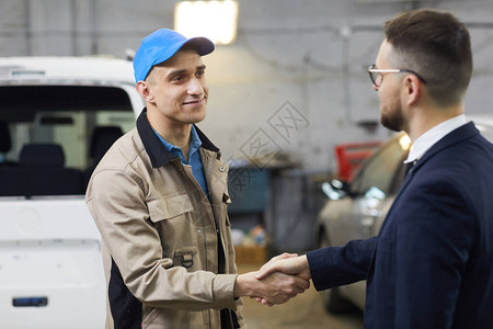 在汽车修理店与专业汽车机修车员握手的客户握手打贺礼照片图片
