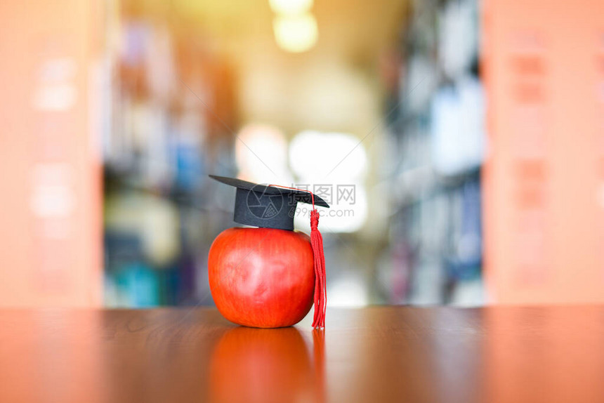 教育学习理念图书馆背景书架桌上苹果毕业帽图片