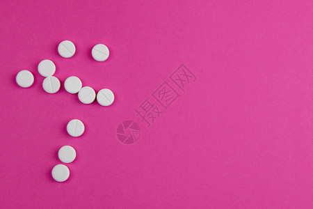 药片散布在粉红色背景上图片