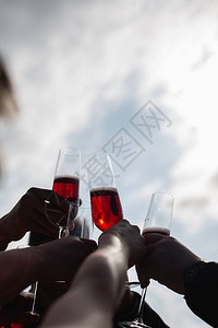 一群人在天空背景上举起杯子和红香槟图片