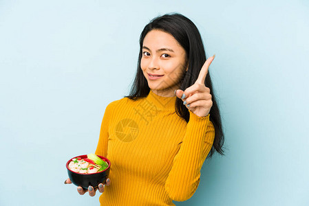 拿着面条的年轻女人独自微笑地欢笑着带图片