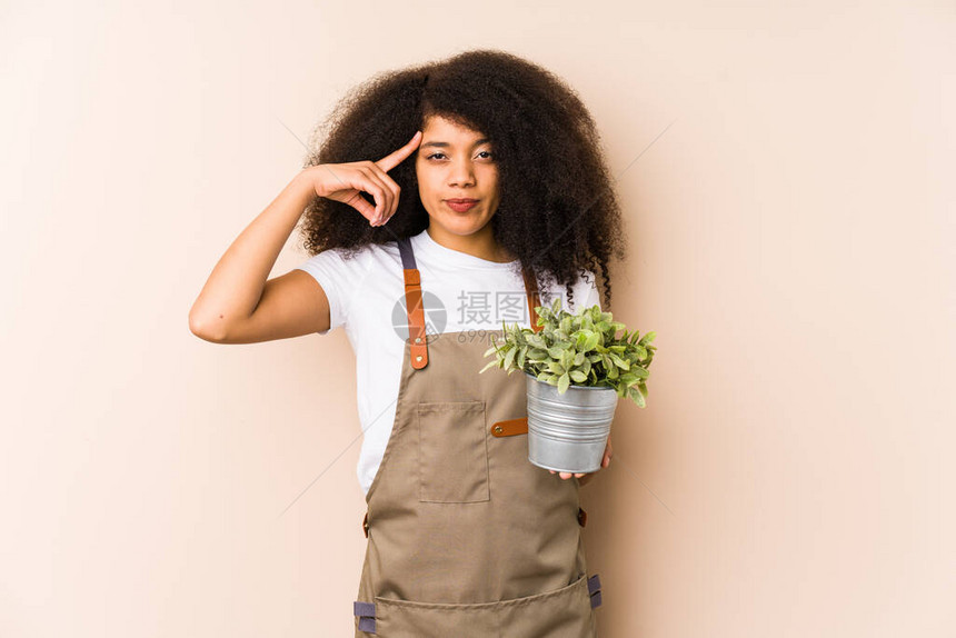 年轻的阿夫罗园丁女人拿着一个植物隔离的用手指图片