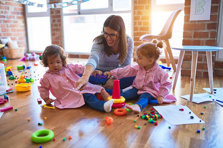 穿着校服建筑金字塔的年轻美丽的教师和幼儿图片