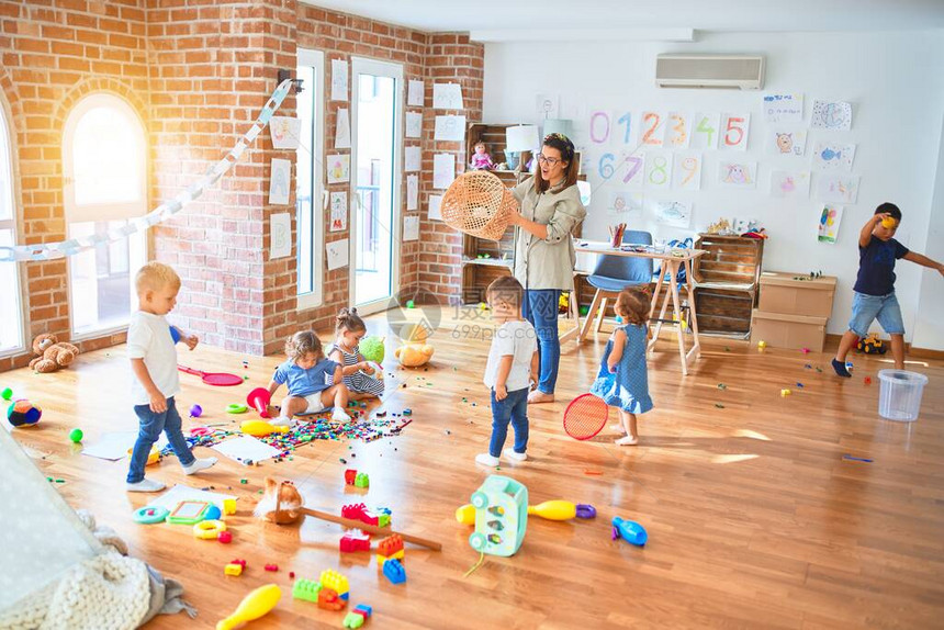 美丽的老师和一群幼童在幼儿园玩很多玩具图片