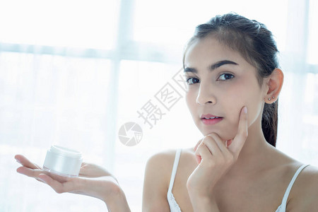 使用皮肤护理产品润湿剂或润滑剂来照顾干肤色的美丽的女亚洲人图片