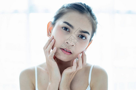 使用皮肤护理产品润湿剂或润滑剂来照顾干肤色的美丽的女亚洲人图片