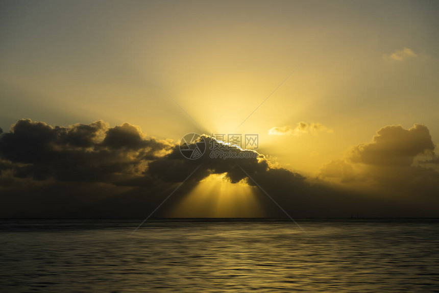 在湖边的日落乌云中的太阳光线图片