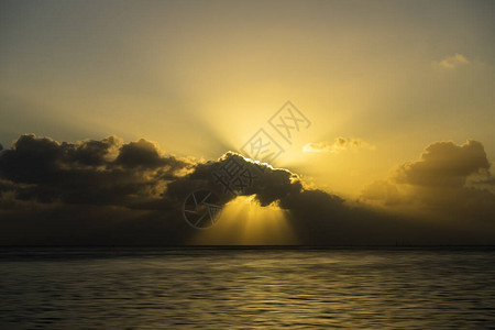 在湖边的日落乌云中的太阳光线图片