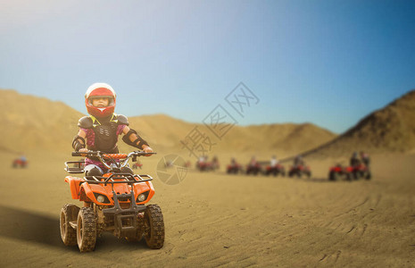 在沙漠中骑着ATV四轮自行车的小女孩美图片