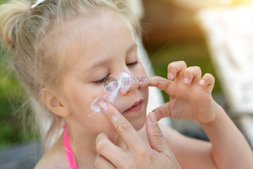 妈在可爱的小女儿鼻子脸上涂防晒霜妈在暑假期间使用防晒乳液保护小女孩免受阳光照射旅行图片