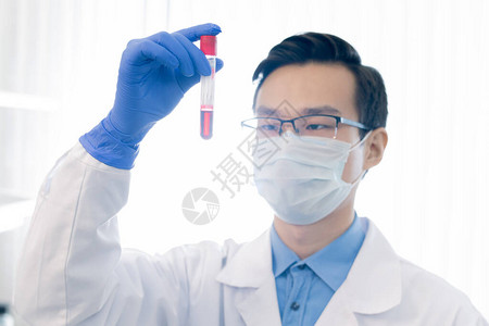 佩戴眼镜保护面罩和带有红色液体的手套持有测试管的亚洲药理学图片