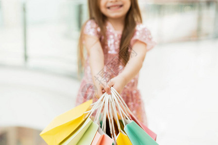 漂亮微笑的小女孩带着购物袋在店里摆姿势图片