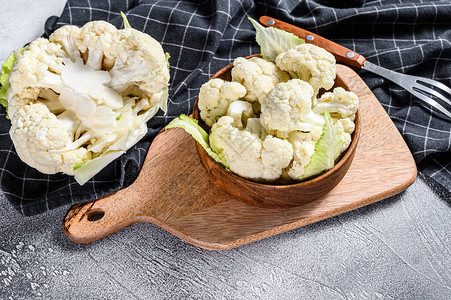 新鲜的有机花椰菜在木碗里切成小块白色背图片