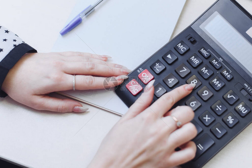 一个女人在计算器上考虑成本收入支出家庭预算分配女企业家图片