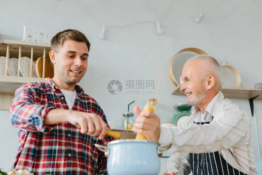 年轻人和他的父亲在厨房做饭图片