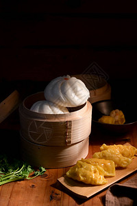 木桌上传统蒸笼上的点心自制饺子和包图片