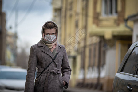 戴着防护医用口罩的年轻漂亮女人站在一辆车旁预防流感冠图片