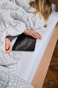 女人手里拿着平板电脑早上在家进行在线活动在床上放松图片