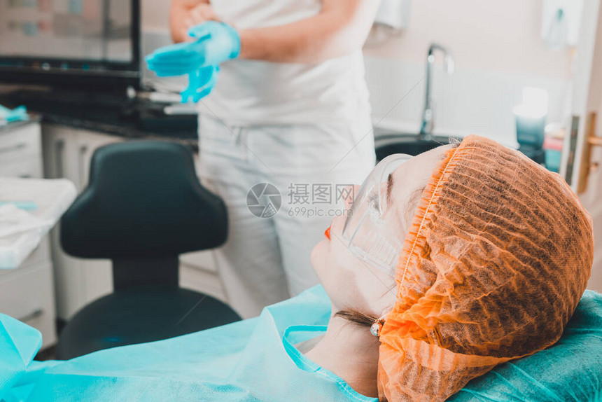 一个可爱的女孩坐在牙医的椅子上等待牙医图片