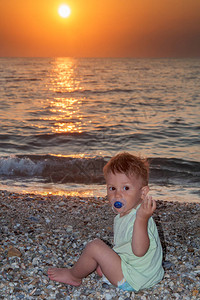 婴儿男孩坐在海滩上图片
