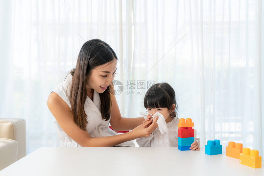 一张剪裁过的亚洲女孩和妈往餐巾纸里吹鼻涕的画像图片