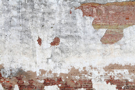 褪色的白色裂缝灰泥和红砖花园墙图片