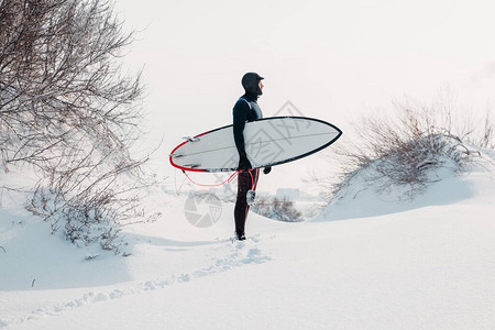 寒冷的冬天和带冲浪板的男冲浪者图片