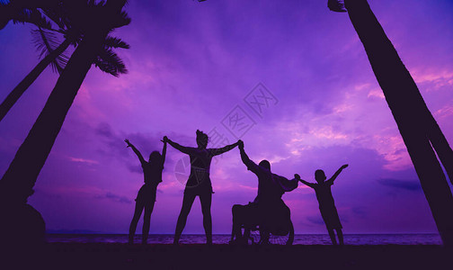 与家人一起坐在轮椅上的残疾人在沙滩上图片