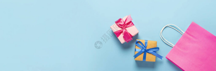蓝色背景上的粉红色袋子和包装盒礼品袋和盒子假期购物销售折扣的概念横幅图片