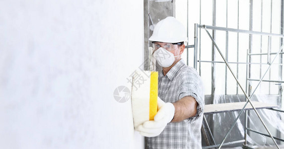 男子建筑工人建筑工人在墙上使用海绵图片