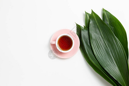 白色背景上有新鲜绿叶的黑茶杯平面最高视图图片