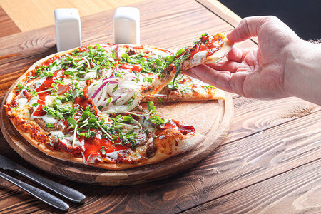 木板上配有培根和草药的披萨奶酪和番茄图片