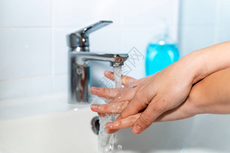 妇女用抗菌肥皂在家中洗手图片