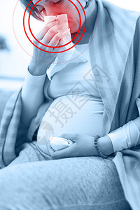怀孕疲劳的孕妇在沙发上肚子和头部有图片
