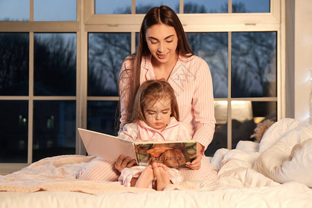 母亲和女儿在家看睡前故事图片