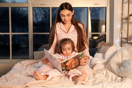 母亲和女儿在家看睡前故事图片