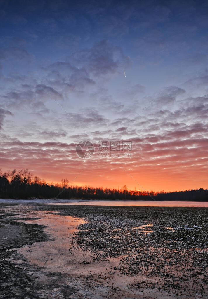 冬天寒冷的日落在冰冻的湖面上美丽的天空和阳光照耀在图片