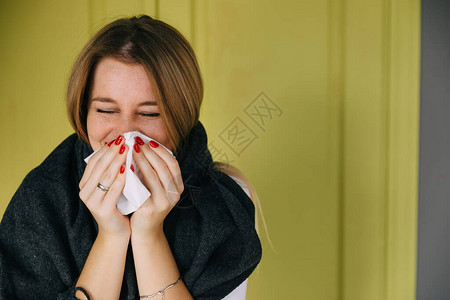 绿色背景的白种病女孩用手帕擤鼻涕患流感图片