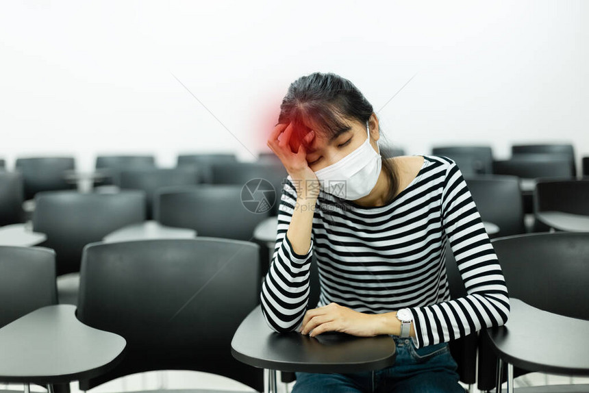身戴卫生面具的年青女子在会议室坐着头痛图片