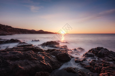 太阳落山时波浪冲上科尔西卡岩石海岸线的长线图像图片