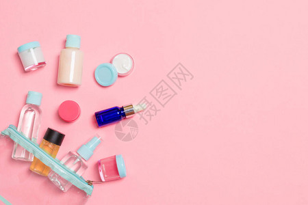 一组用于在粉红色背景上旅行的小瓶子为您的想法复制空间化妆品的平躺组合物带化妆棉的奶油背景图片