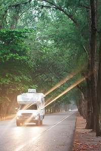 黄昏时在松树路上开露营车图片