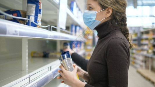 一名身戴医疗面具的妇女拿走了超市最后一袋食物背景图片