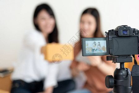 数码摄像机特写镜头记录两个女孩展示新产品广告Vlog和影响者的概念人们兼职工作和职业使用现代技术背景图片