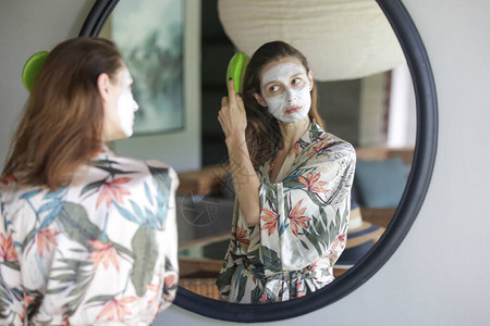 在镜子前梳理头发的面部美容面具图片